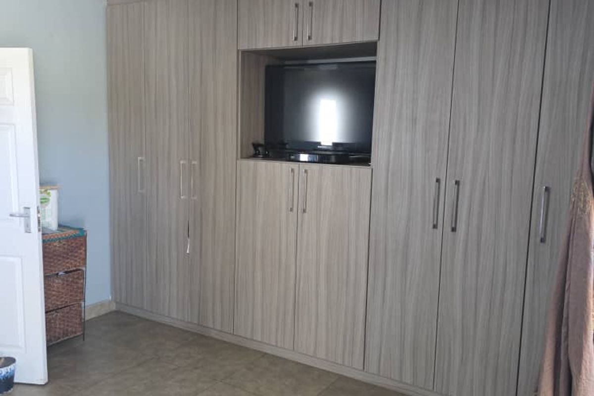 A bedroom featuring extensive built-in cabinetry with a central media nook, tiled flooring, and recessed ceiling lighting.