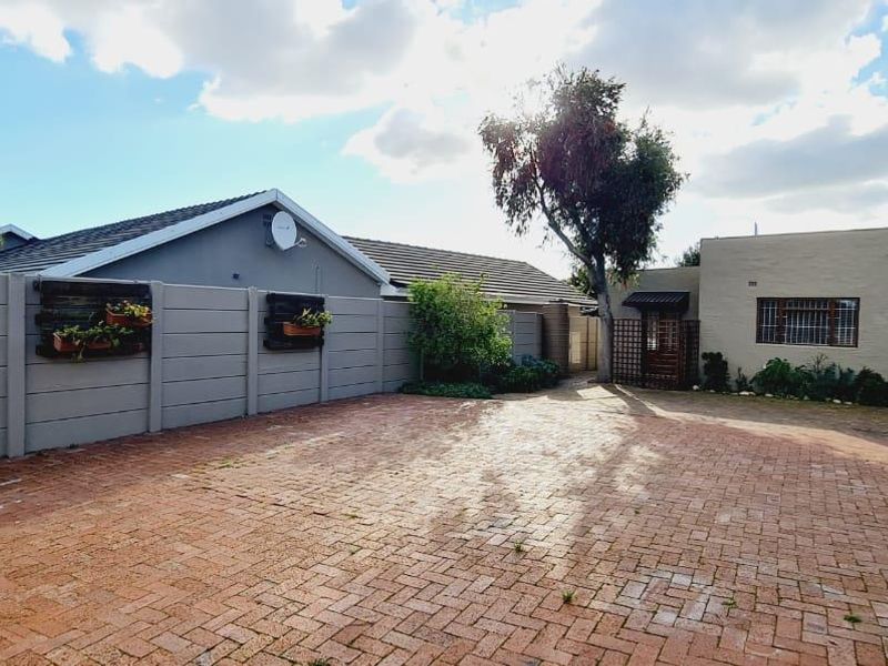 A paved rear courtyard area featuring a precast concrete boundary wall and access to the main building structure with security-fitted windows.