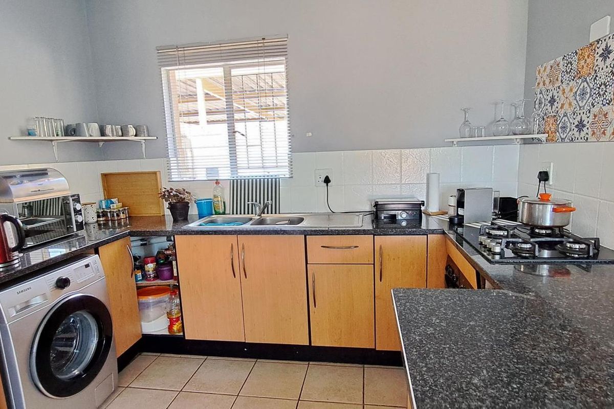 Functional kitchen featuring wood-finish cabinetry, granite countertops, a gas hob, and tiled backsplash, providing a practical workspace for daily cooking.