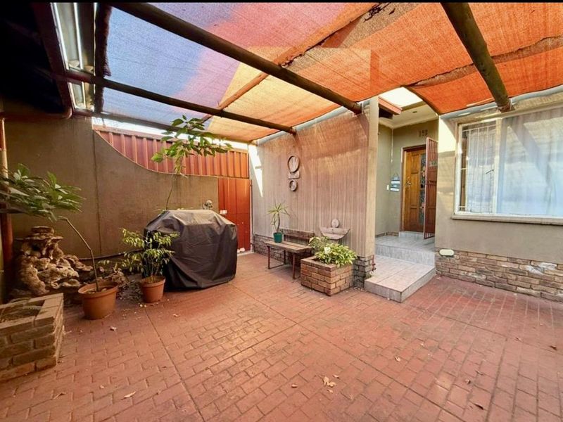 Covered outdoor patio area featuring brick paving, a shade cloth canopy, and direct access to the main entrance of the home.