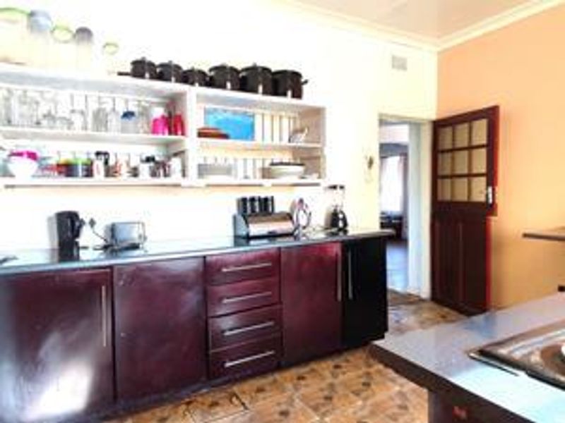A functional kitchen featuring dark built-in cabinetry, open shelving, and tiled flooring, providing a practical workspace with potential for modern updates.