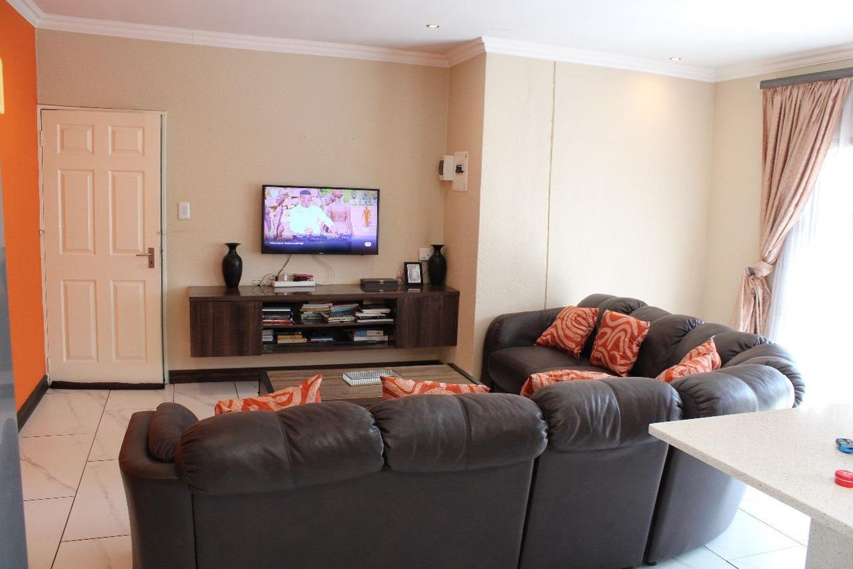 A comfortable living room featuring tiled flooring, recessed ceiling lighting, and a wall-mounted media console.
