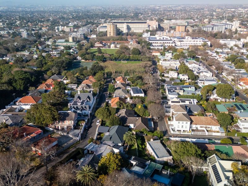 An elevated aerial view showcasing the residential neighborhood, surrounding greenery, and urban landscape context of the property.