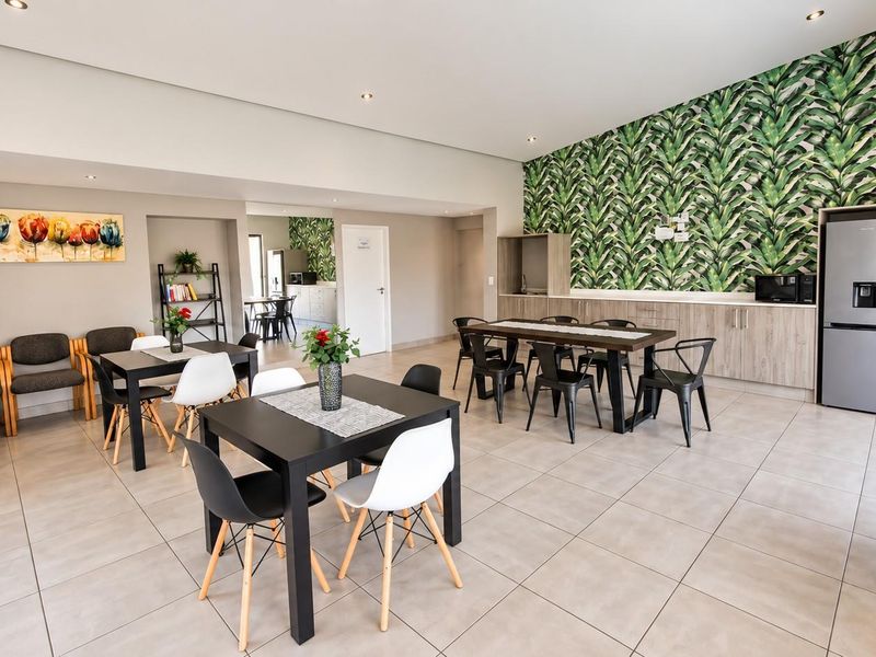 Spacious open-plan living and dining area featuring tiled flooring, recessed lighting, and a functional kitchen section with built-in cabinetry.