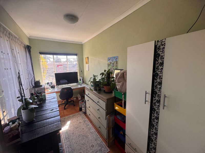 A functional bedroom featuring tiled flooring, a window with security bars, and coved ceiling detailing.