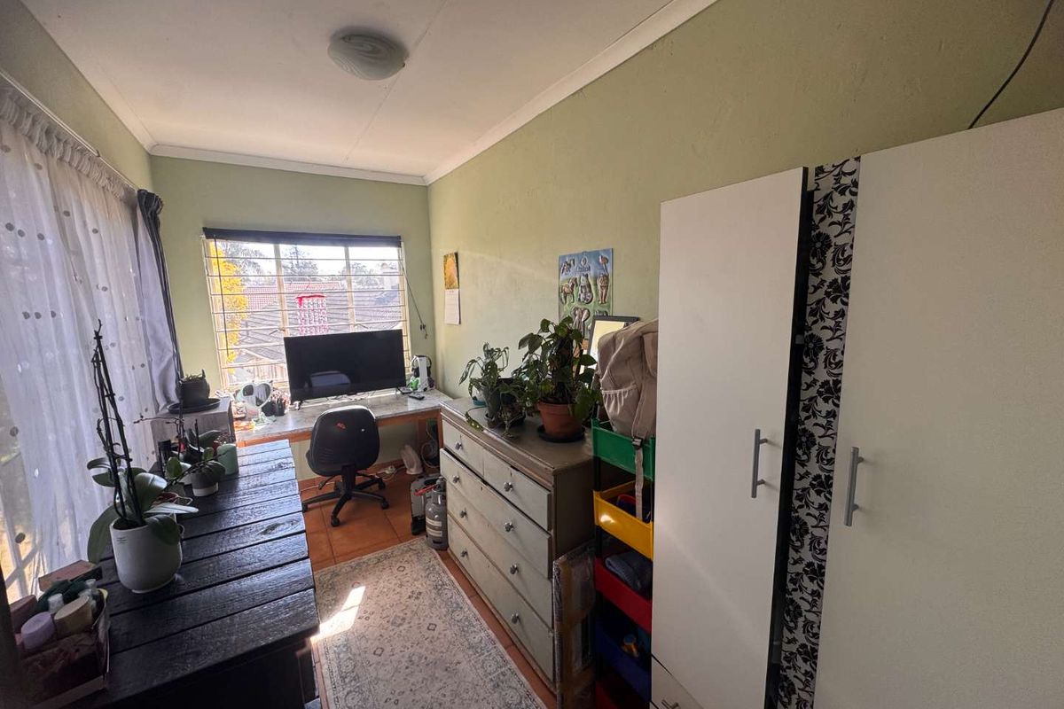 A functional bedroom featuring tiled flooring, a window with security bars, and coved ceiling detailing.
