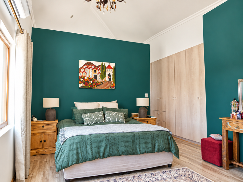 Spacious bedroom featuring built-in cupboards, laminate flooring, and a feature wall with air conditioning.