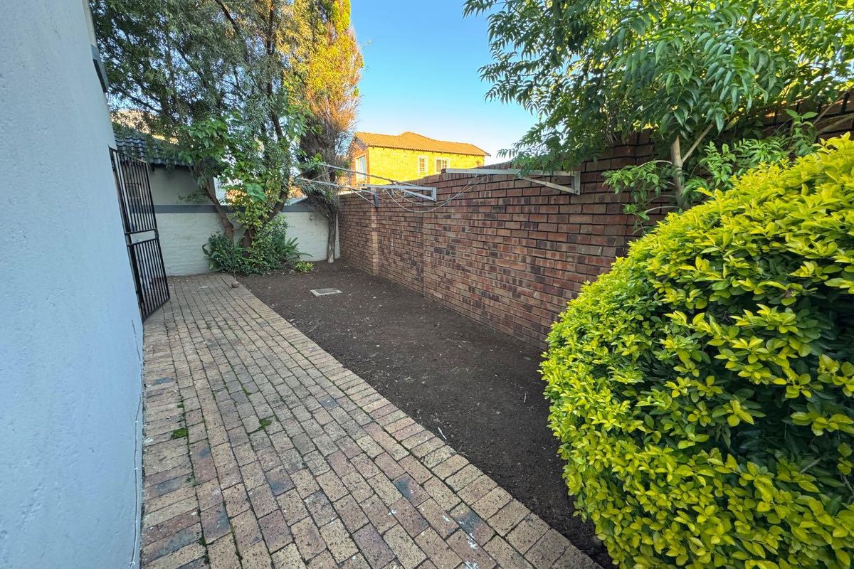 A private rear garden area featuring brick paving, a perimeter brick wall, and a wall-mounted washing line.