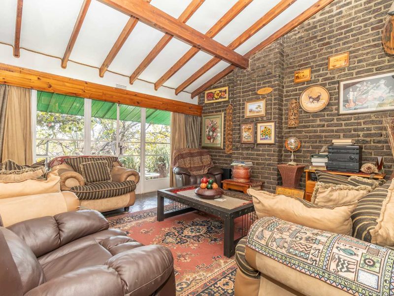 Spacious living room featuring an exposed brick feature wall, vaulted ceiling with timber beams, and large sliding glass doors providing natural light.
