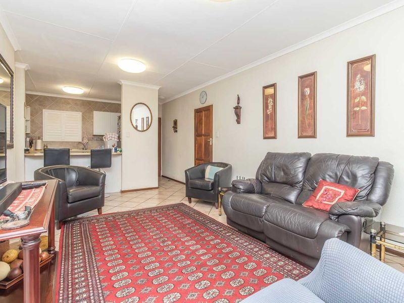 Open-plan living area featuring tiled flooring and a connected kitchen with a breakfast bar, offering a functional and versatile layout.