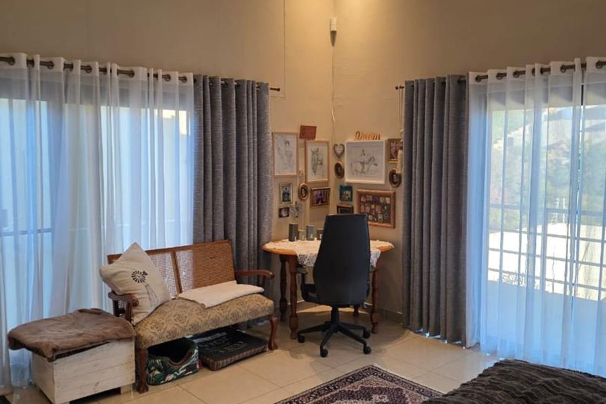 Spacious bedroom featuring high ceilings, tiled flooring, and dual sliding glass doors providing ample natural light and access to the outdoors.