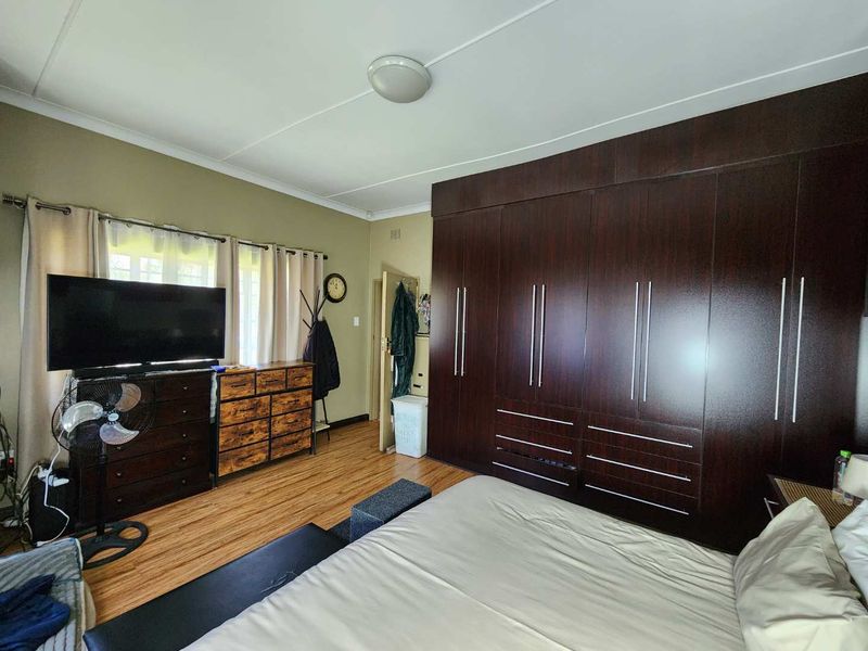 A bedroom featuring extensive dark wood built-in cupboards and laminate flooring, providing ample storage space.