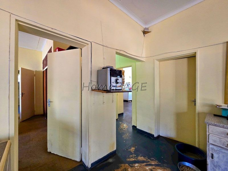 A functional hallway area showing signs of wear, featuring multiple internal doorways and basic finishes, requiring cosmetic updates and maintenance.