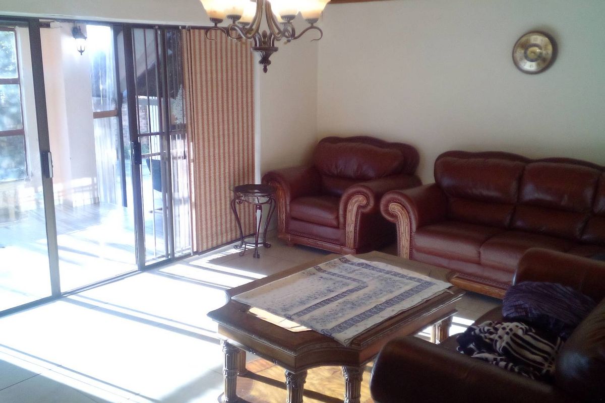 A living room featuring tiled flooring, a timber-paneled ceiling, and large sliding glass doors providing access to an outdoor patio area.