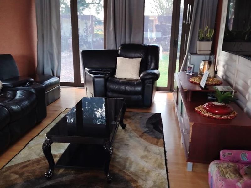 A living room featuring laminate flooring, a textured feature wall, and sliding glass doors providing access to the outdoor area.