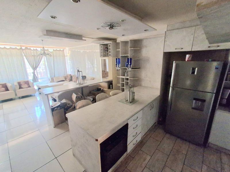 Open plan living and kitchen area featuring a central island, built-in cabinetry, and tiled flooring, offering a functional layout for modern living.