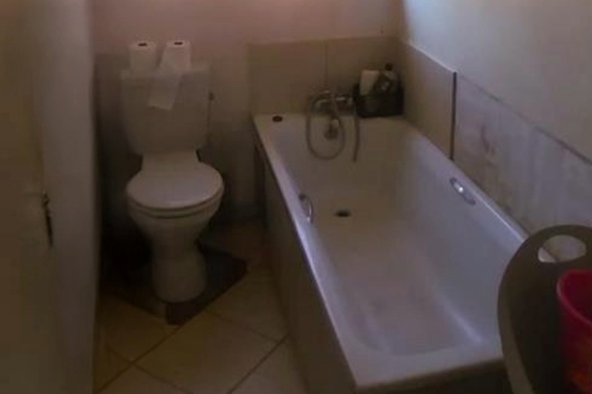 A compact bathroom featuring a standard bathtub with shower mixer and a close-coupled toilet, finished with neutral floor tiles.
