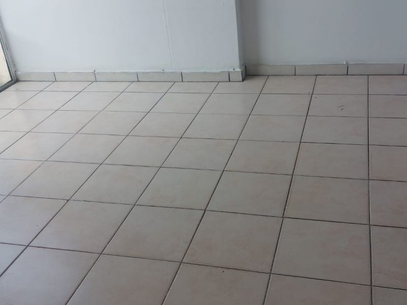 An empty, enclosed patio area featuring tiled flooring and aluminium sliding doors, offering a blank canvas for renovation or outdoor living space design.