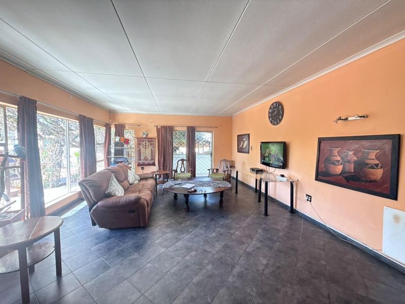 Spacious living room featuring large windows, tiled flooring, and coved ceilings, offering a bright and functional area for relaxation.