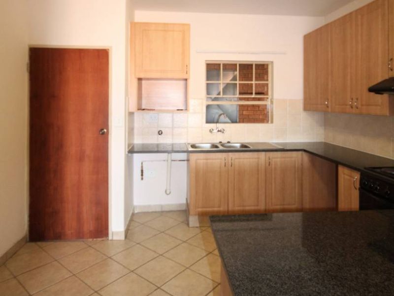 A functional kitchen featuring laminate cabinetry, granite countertops, a double bowl sink, and tiled flooring, offering a practical layout for renovation.