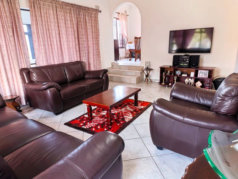 Spacious living room featuring tiled flooring and an arched transition to an elevated dining area, providing a functional and open layout.