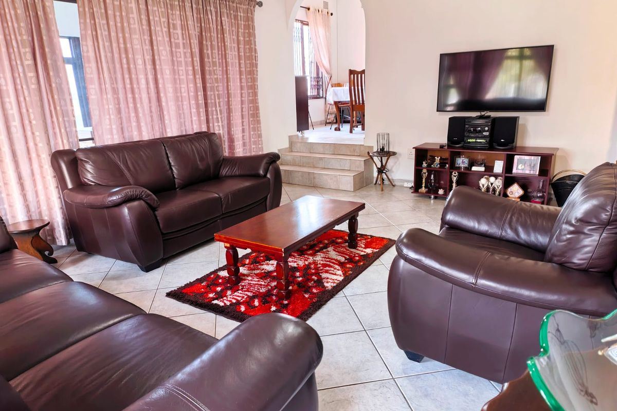 Spacious living room featuring tiled flooring and an arched transition to an elevated dining area, providing a functional and open layout.