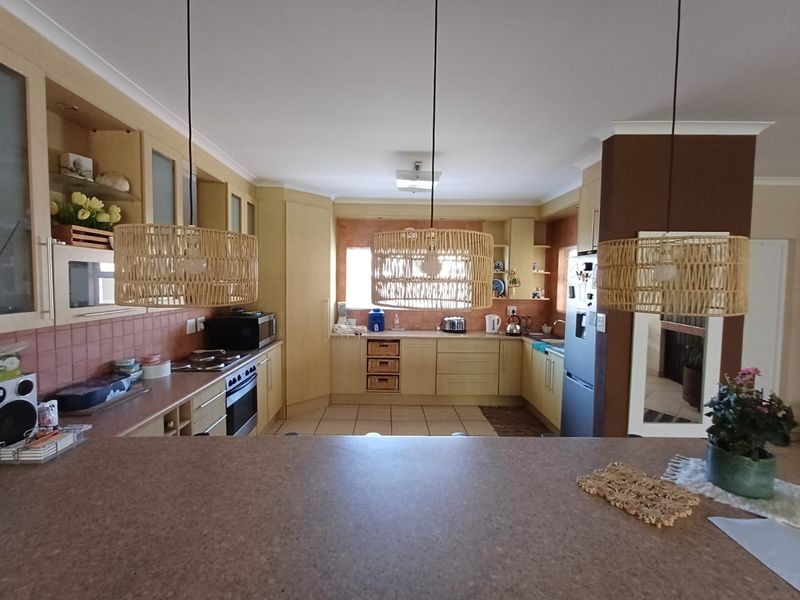 A functional kitchen featuring light-toned cabinetry, tiled backsplash, built-in oven, and a breakfast bar, offering a practical layout for daily cooking and dining.