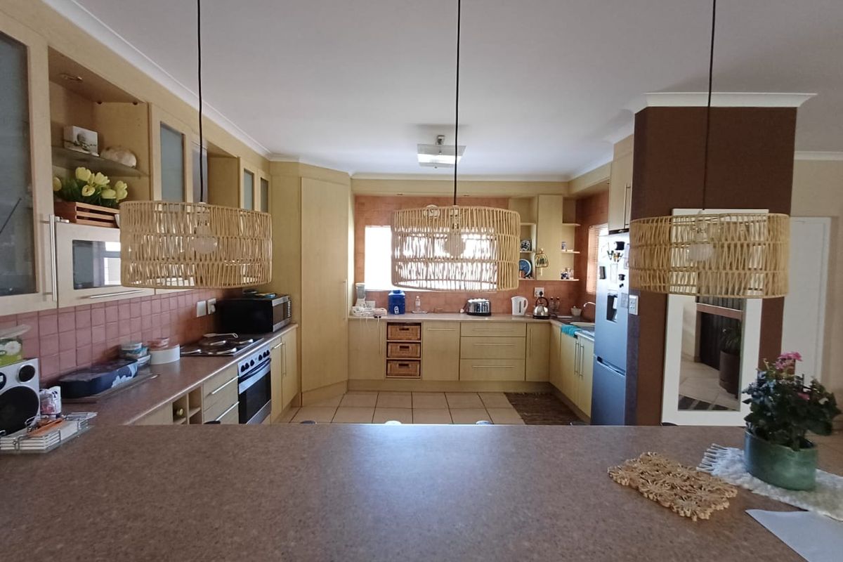 A functional kitchen featuring light-toned cabinetry, tiled backsplash, built-in oven, and a breakfast bar, offering a practical layout for daily cooking and dining.