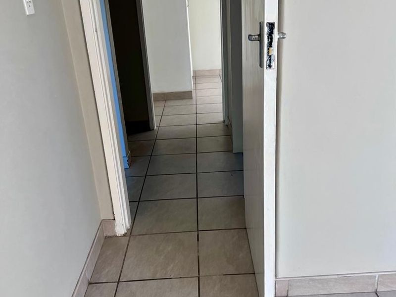 A vacant hallway featuring tiled flooring and neutral walls, providing access to adjacent rooms within the apartment.