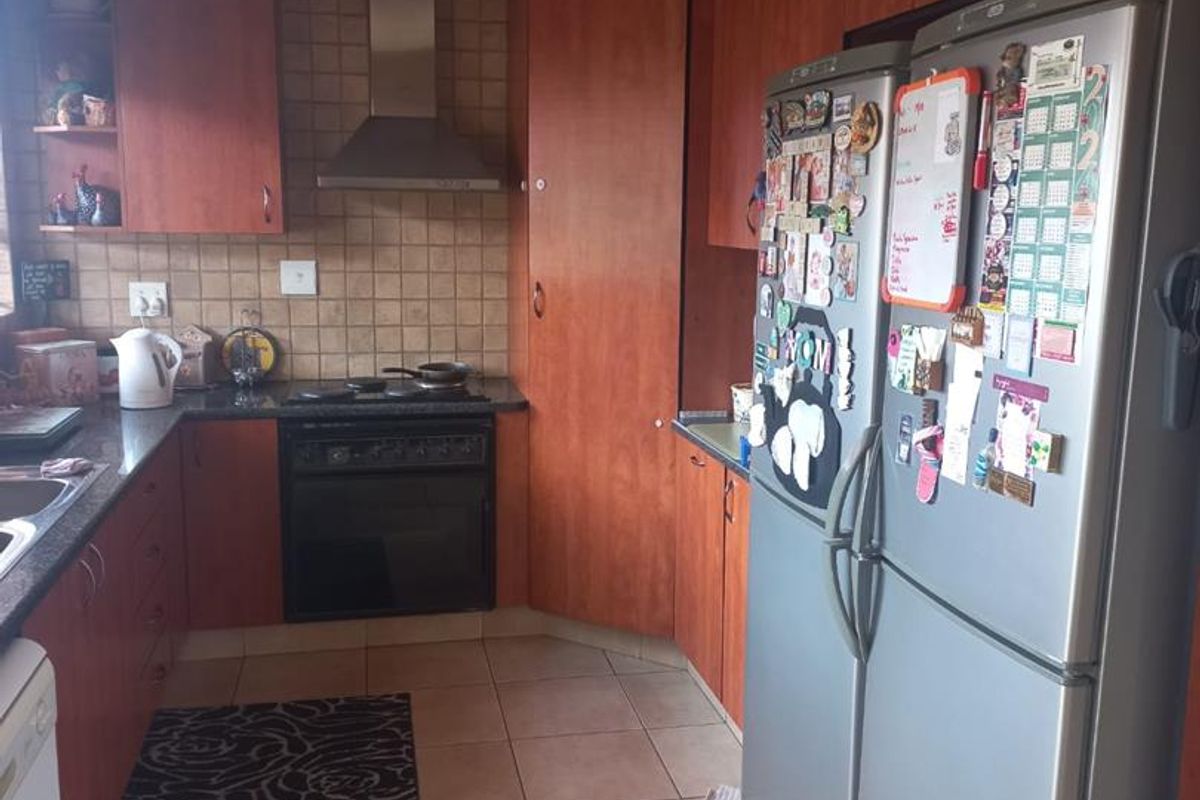 A functional kitchen featuring wood-finish cabinetry, granite countertops, a stainless steel extractor fan, and a built-in oven with a tiled backsplash.