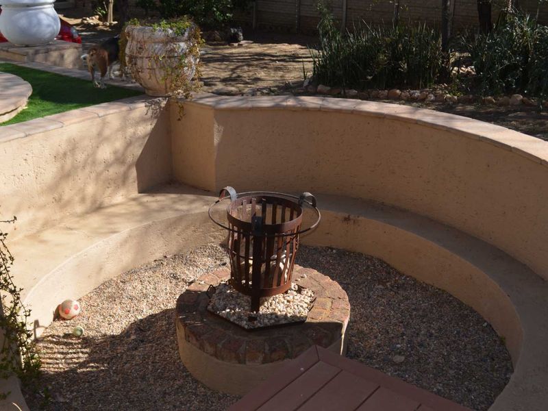 Outdoor entertainment area featuring a built-in curved seating wall and a central brick fire pit base set within a gravel courtyard.