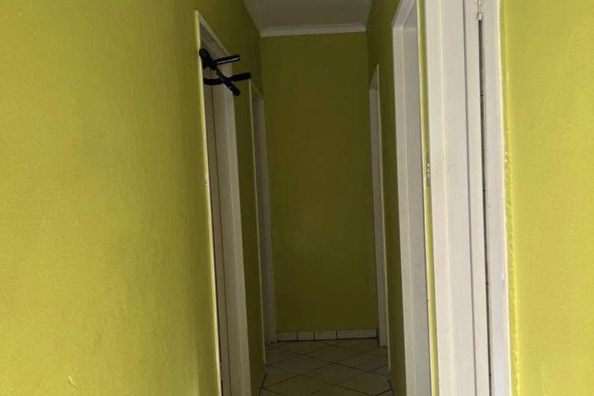 A narrow interior hallway featuring tiled flooring and multiple doorways, currently finished with bright green wall paint.