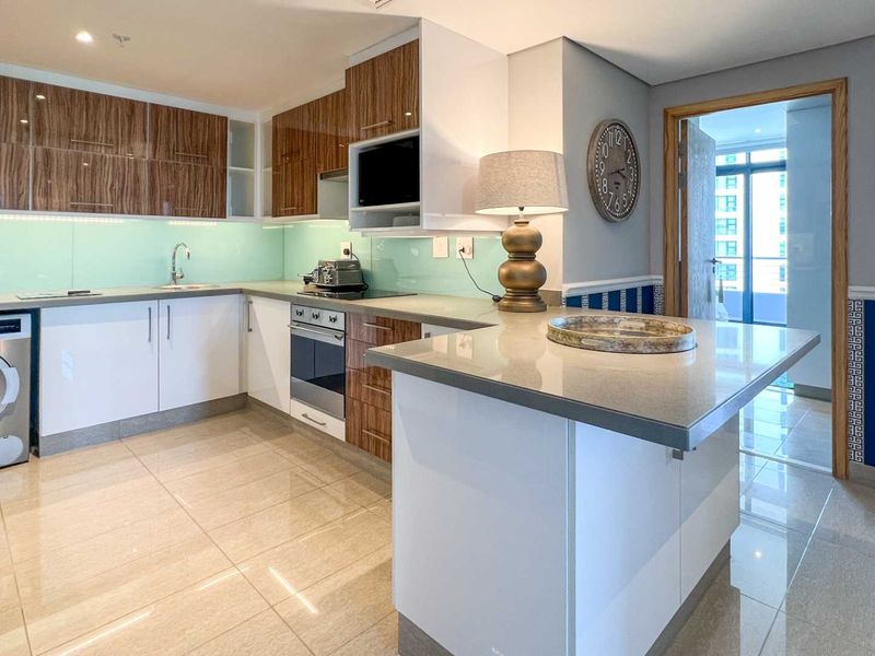 Modern kitchen featuring wood-grain and white cabinetry, stone countertops, a glass splashback, and an integrated washing machine.
