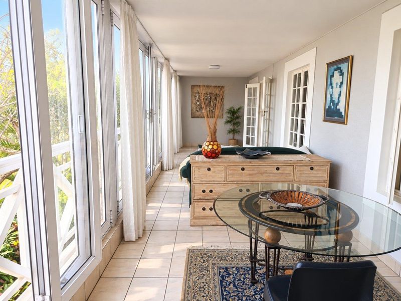 A bright and spacious enclosed balcony featuring large glass sliding doors, tiled flooring, and direct access to the interior living space.