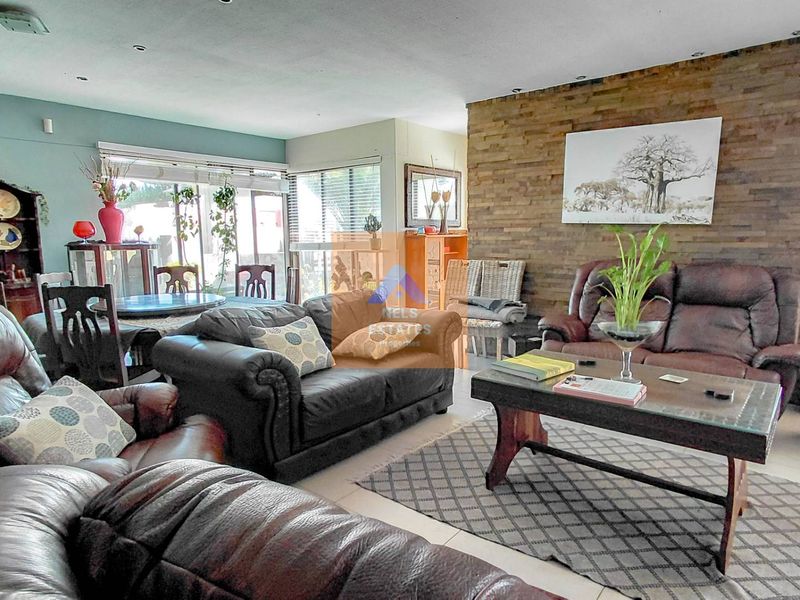 Spacious open-plan living and dining area featuring a prominent stone feature wall, tiled flooring, and large sliding glass doors providing natural light.