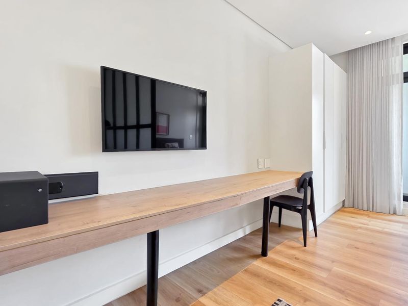 Modern bedroom featuring a sleek floating timber desk, built-in wardrobe, and high-quality timber flooring with integrated curtain tracks.