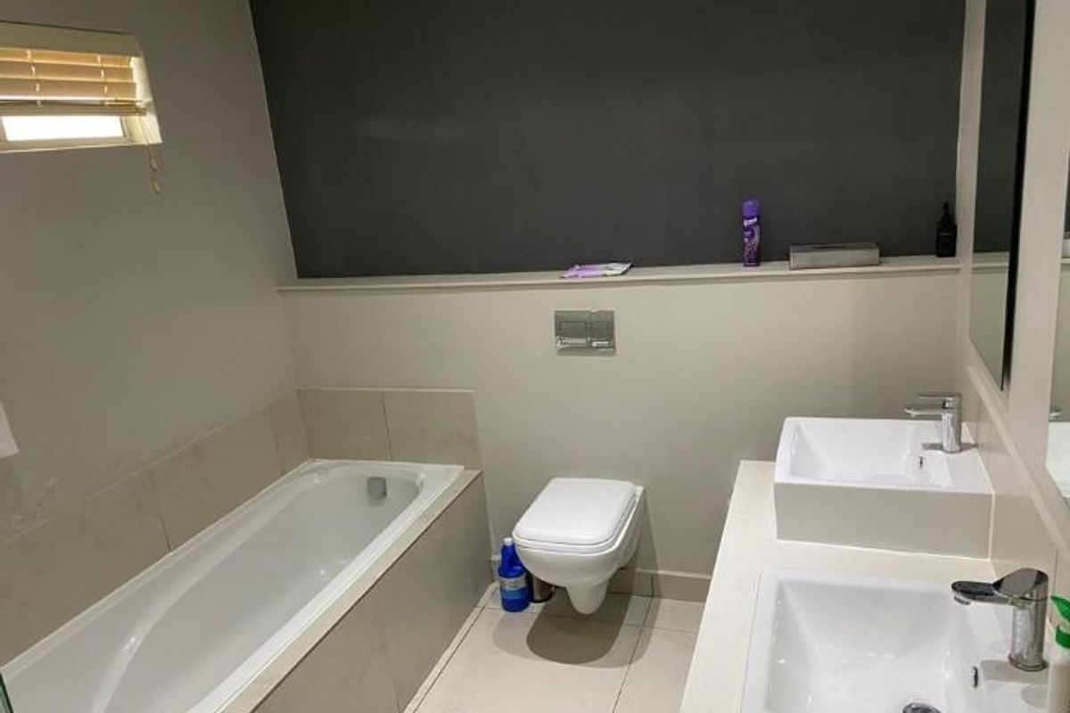 Modern bathroom featuring a built-in bathtub, wall-mounted toilet, and a double vanity with dual vessel sinks.