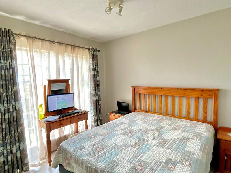 A functional bedroom featuring tiled flooring, a ceiling light fixture, and a sliding glass door providing natural light.