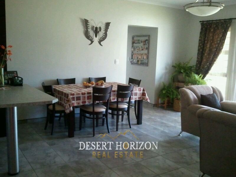 Open plan living and dining area featuring tiled flooring and a breakfast counter, providing a functional space for daily living and entertaining.