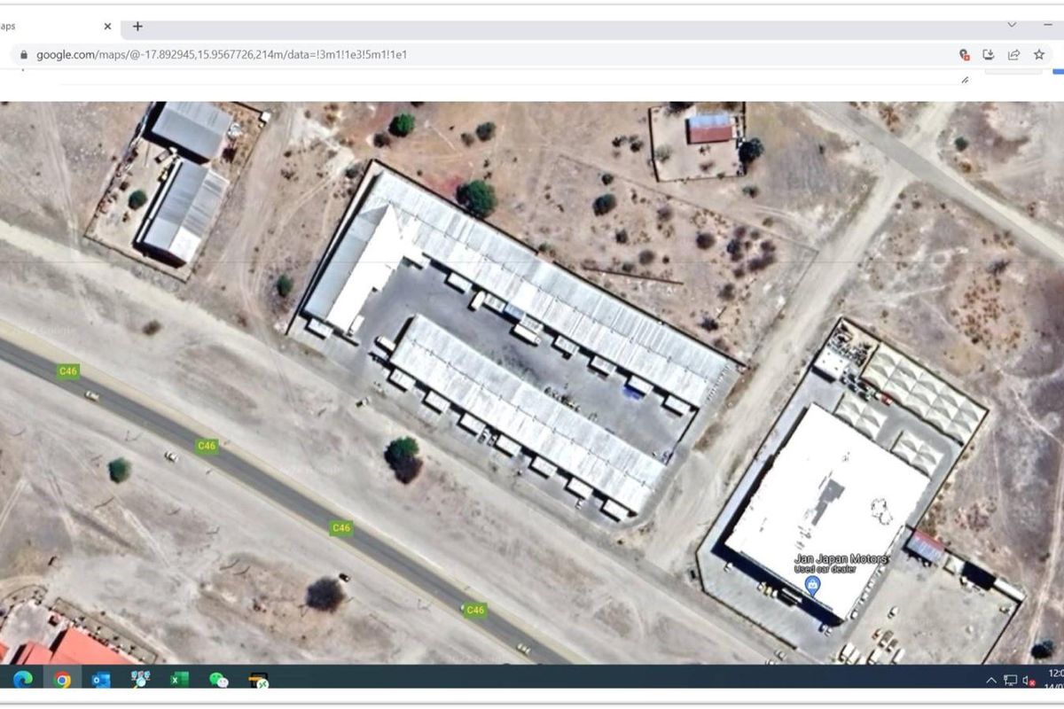 Aerial view of an industrial property complex featuring multiple warehouse units and paved yard space, situated adjacent to a main road.