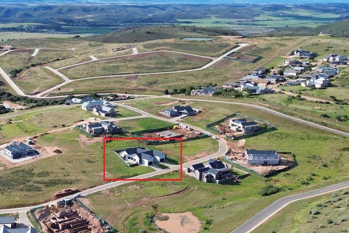 Aerial view of a modern residential property situated within a developing estate, featuring a paved driveway and surrounding landscaped grounds.