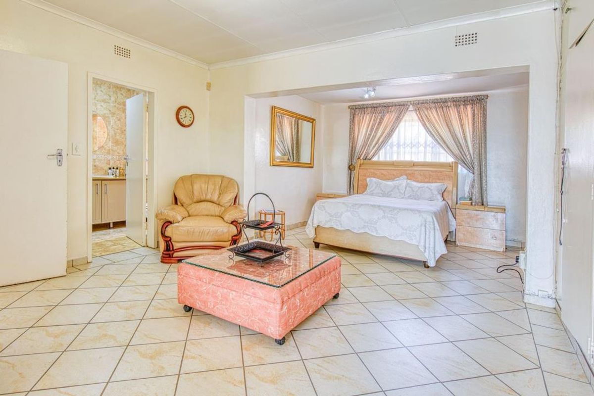 Spacious bedroom featuring tiled flooring, an integrated en-suite bathroom, and a recessed sleeping area with natural light.