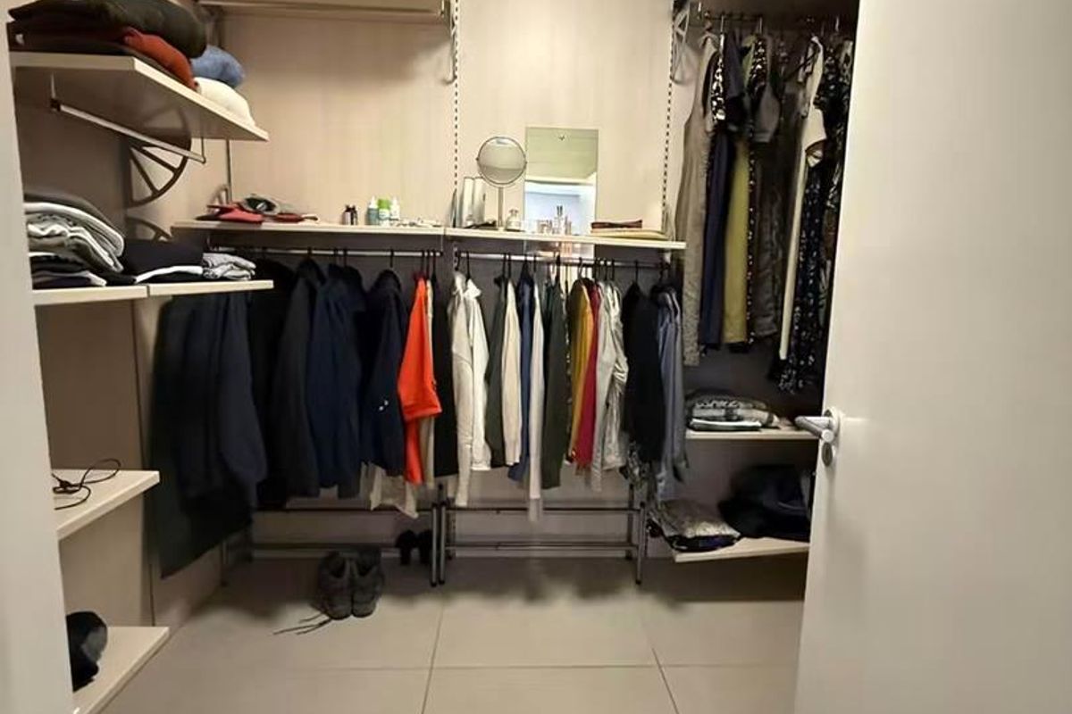 A functional walk-in closet featuring organized built-in shelving, hanging rails, and neutral tiled flooring.