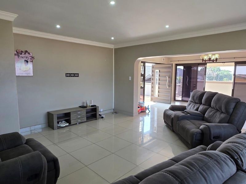Spacious living room featuring neutral walls, tiled flooring, recessed downlighting, and an open archway leading to an outdoor patio area.