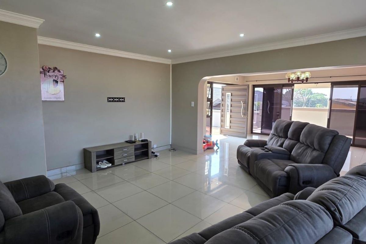 Spacious living room featuring neutral walls, tiled flooring, recessed downlighting, and an open archway leading to an outdoor patio area.