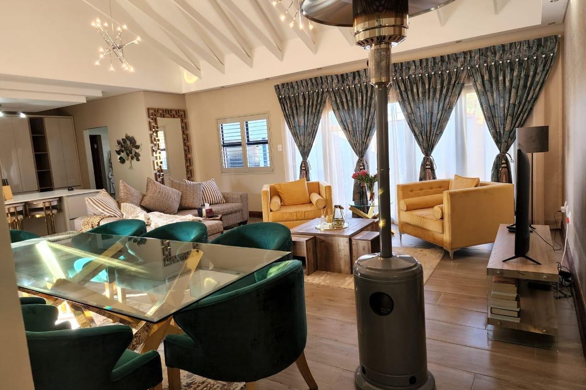 Spacious open-plan living and dining area featuring vaulted ceilings, tiled flooring, and large windows with elegant drapery.