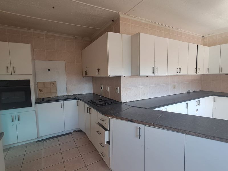 A spacious kitchen featuring built-in cabinetry, a gas hob, and an integrated oven, offering a functional layout ready for modern updates and cosmetic renovation.