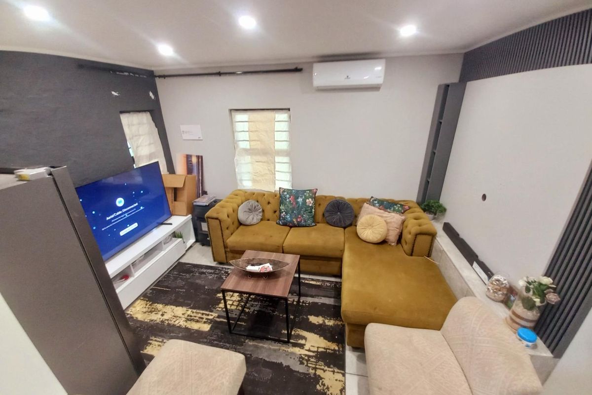 A living room featuring a dark accent wall, recessed ceiling lighting, and a wall-mounted air conditioning unit.