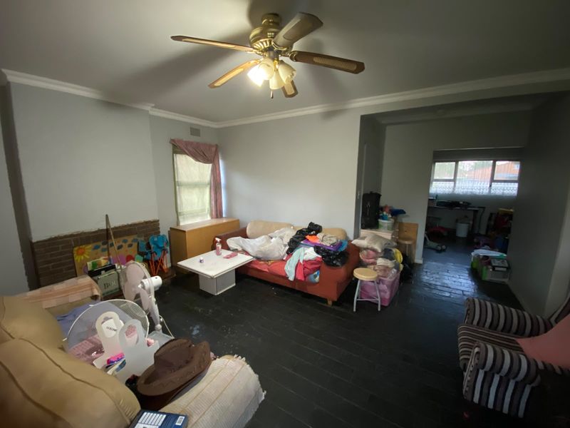 Spacious living room featuring a brick fireplace, ceiling fan, and dark slate flooring, offering a versatile layout for comfortable family living.