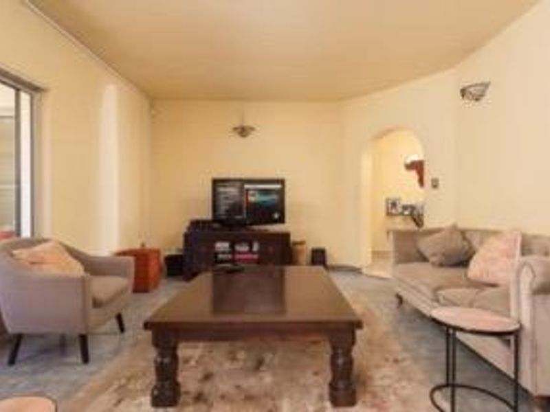 A spacious living room featuring an arched entryway, wall sconce lighting, and a sliding glass door providing access to the outdoor area.
